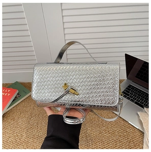 Detail of silver woven texture handbag with golden knot hardware and shoulder strap