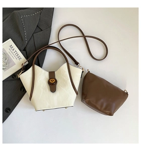 Close-up of minimalist bucket bag with textured leather, turn-lock, and inner pouch