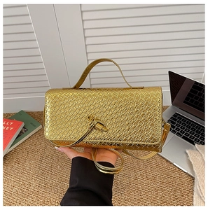 Detailed view of woven texture on a metallic gold baguette bag held by hand