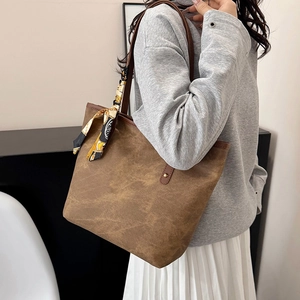 Brown large capacity tote bag with decorative silk scarf on shoulder in modern interior
