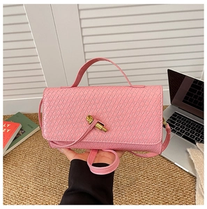 Macro detail of pink woven leather handbag with gold twist lock and top handle