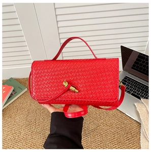 Macro detail of red woven faux leather handbag with golden knot buckle and strap