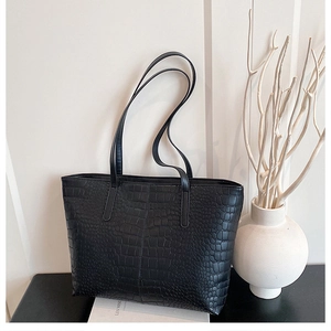 Detail of large black crocodile pattern tote bag with shoulder strap for commuting
