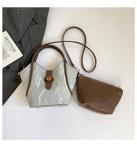 Detailed top view of a pleated bucket bag set with brown leather handles and inner pouch