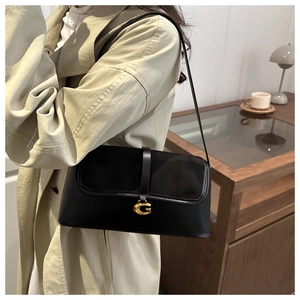 Detail of black underarm bag featuring premium leather patchwork and golden G buckle