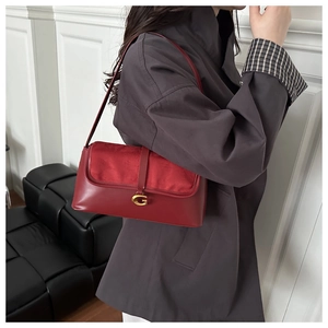 Detail of red leather shoulder bag featuring a gold G buckle and textured fabric flap
