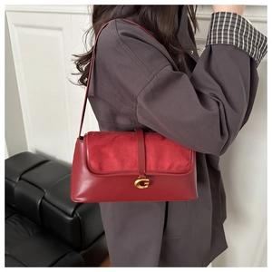 Detail of red leather and suede baguette bag with gold G-logo clasp on a model
