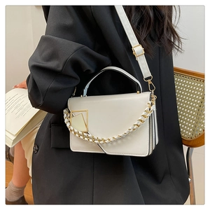 Detail van de witte lederen crossbodytas met gouden ketting en vierkante metalen gesp
