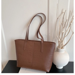Close-up of brown crocodile pattern faux leather tote bag with long shoulder straps