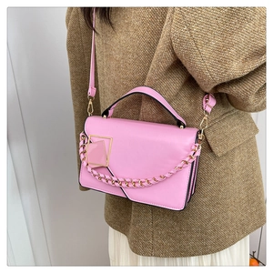 Detail van roze crossbodytas met gouden ketting en geometrische metalen gespsluiting