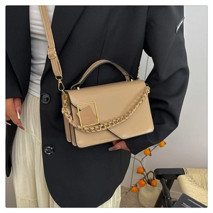 Detail van de kaki PU-leren tas met gouden ketting op een zwarte blazerjas
