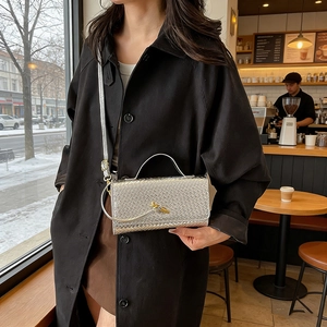 Silver woven leather baguette handbag with golden knot clasp shown on model