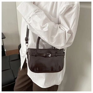 Détail d'un sac à main en cuir brillant marron foncé avec boucle et bandoulière réglable