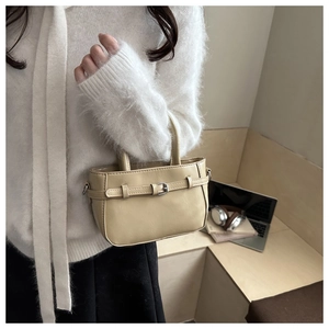 Close-up of beige PU leather handbag with silver metallic buckle and dual handle design