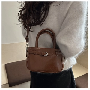 Close-up of brown PU leather handbag with silver buckle and adjustable shoulder strap