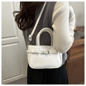Detailed side view of white faux leather crossbody bag with buckle on a model