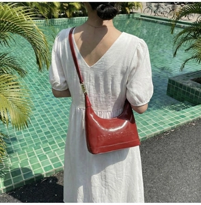 Detail view of burgundy pillow bag with maison embossing on a shoulder strap model
