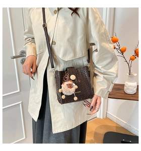 Detail of dark brown woven bucket bag with wood button and sheep plush pendant charm