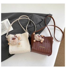 Detailaufnahme der geflochtenen Lederstruktur kleiner Beuteltaschen mit Bärenanhänger