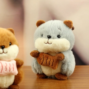 Close-up of cute plush hamster keychain holding a brown fish accessory on wood surface
