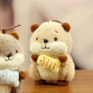 Close-up of cute plush hamster charm with soft fur and a small yellow fish accessory