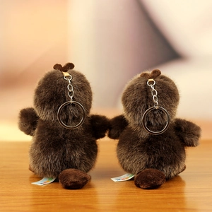 Détail de deux porte-clés ornithorynques en peluche sur bois avec focus sur la texture