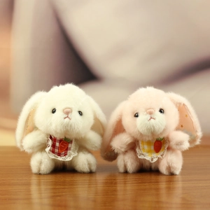 Plush bunny keychains in white and pink with plaid bibs on a cozy wooden surface