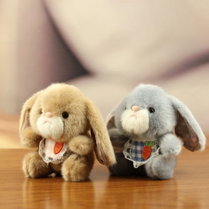 Close-up of cute plush bunny charms with lace bibs and detailed carrot embroidery