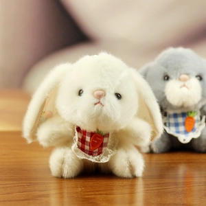 Close-up of cute plush bunny toys with lace bibs and carrot embroidery on soft fur
