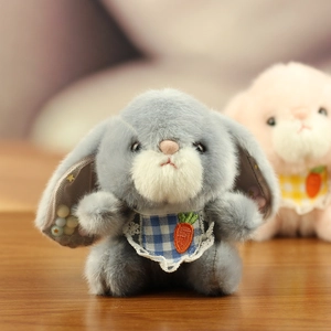 Close-up of grey plush bunny with carrot embroidery and blue plaid lace bib detail