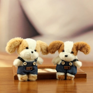 Pluche hondenknuffel met denim tuinbroek en houten knopen op houten achtergrond