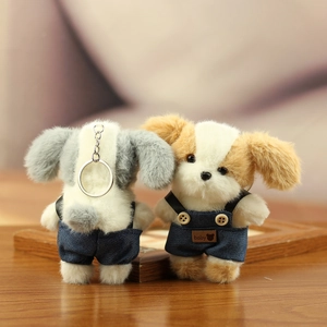 Detailweergave van pluche puppy-sleutelhangers in denim overals met baby-labels en ringen