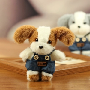 Detail van de pluche puppy in denim overall met houten knopen en een baby-label