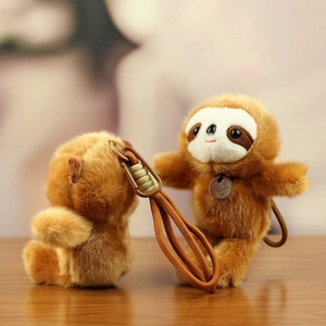 Cute brown plush sloth keychain with braided strap and metal plate on wooden table