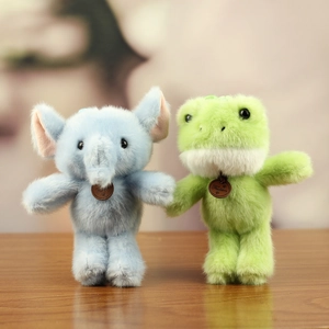 Close-up of soft plush elephant and frog toys with leather tags on a wooden table