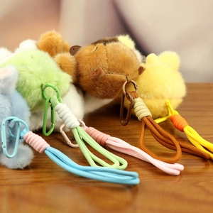 Detail of plush animal keychain pendants in blue, green, brown, and yellow with D-rings