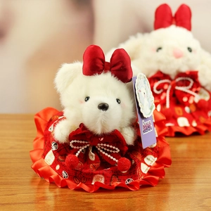 Detail of white plush bear wearing a red patterned dress and a satin bow accessory