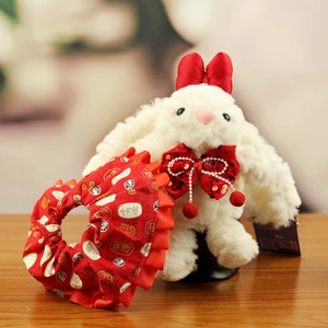 Detail of white plush bunny with red floral hair scrunchie and festive gold characters