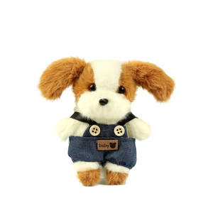 Schattige bruin-witte pluche puppy met een blauwe denim overal en baby-label