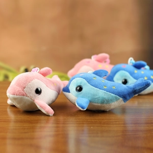 Pink and blue dolphin plush toys with yellow star embroidery on a wooden table