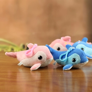 Mini plush dolphin keychains in pink and blue with plastic clips on a wooden surface