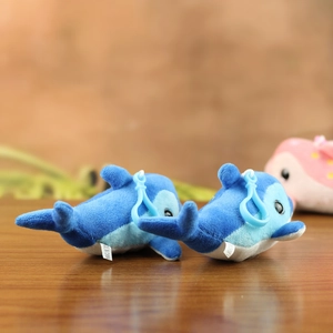 Close-up of blue dolphin plush keychains with plastic hooks and washing labels on wood