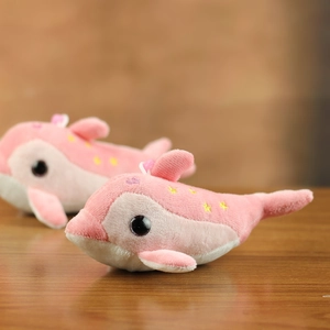 Detail of pink dolphin plush toys with yellow star patterns on a wooden table