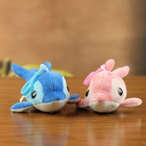 Detail of pink and blue plush dolphin keychains with plastic hooks on wooden desk