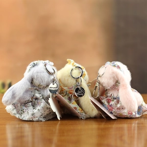 Gros plan détaillé de trois porte-clés lapins en peluche avec robes à fleurs et dentelle