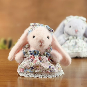 Gros plan d'un lapin en peluche rose avec robe à fleurs et bordure en dentelle blanche