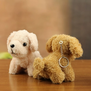 Close-up of curly plush teddy dog keychains in beige and brown on a wooden surface