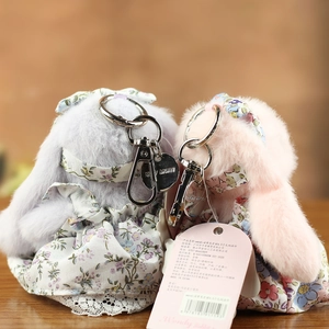 Détail de pendentifs lapin en peluche avec robes à fleurs et plaques en métal