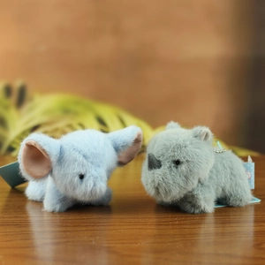 Detail of plush animal keychain with fluffy texture and beaded chain on wood surface