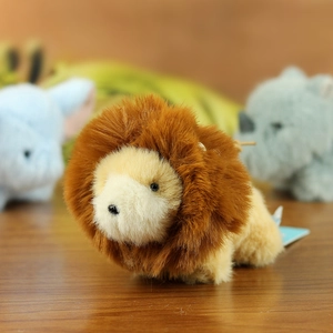 Close-up of a mini plush lion toy with fluffy brown mane on a warm wooden surface